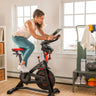 Woman riding the BowFlex C6 Bike and looking at a tablet on the bike's media shelf.