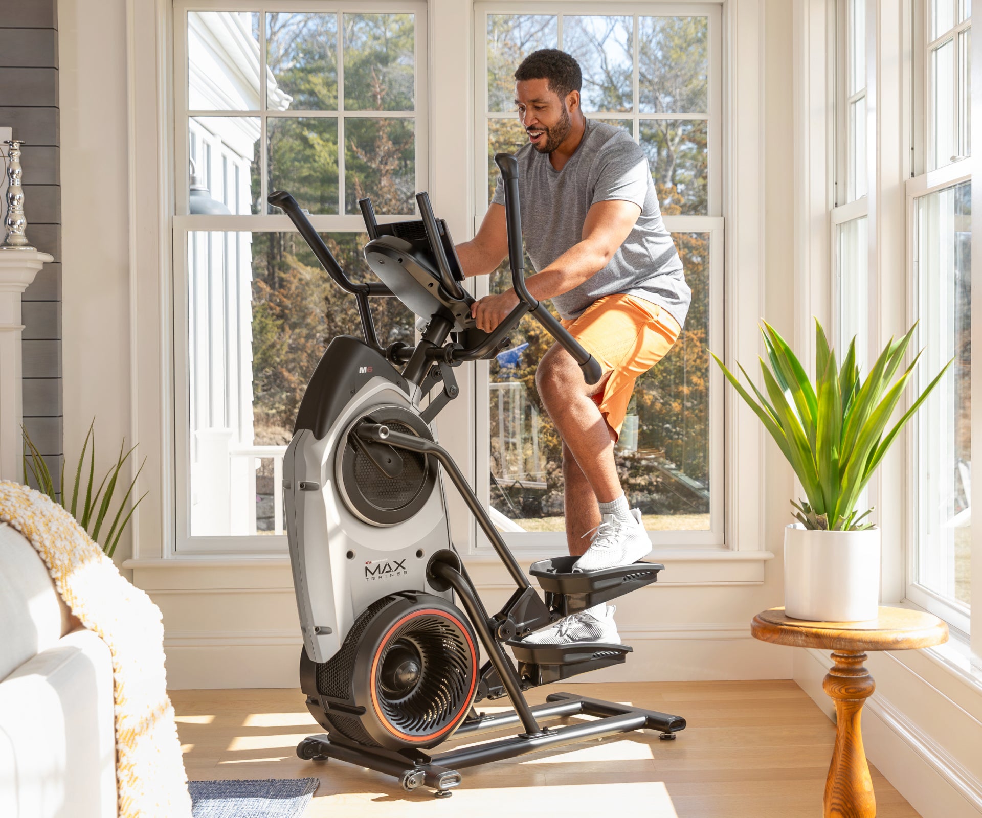Man exercising on a BowFlex Max Trainer M6 in a home setting.