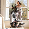 Woman exercising on a BowFlex Max Trainer M6 in a home setting.