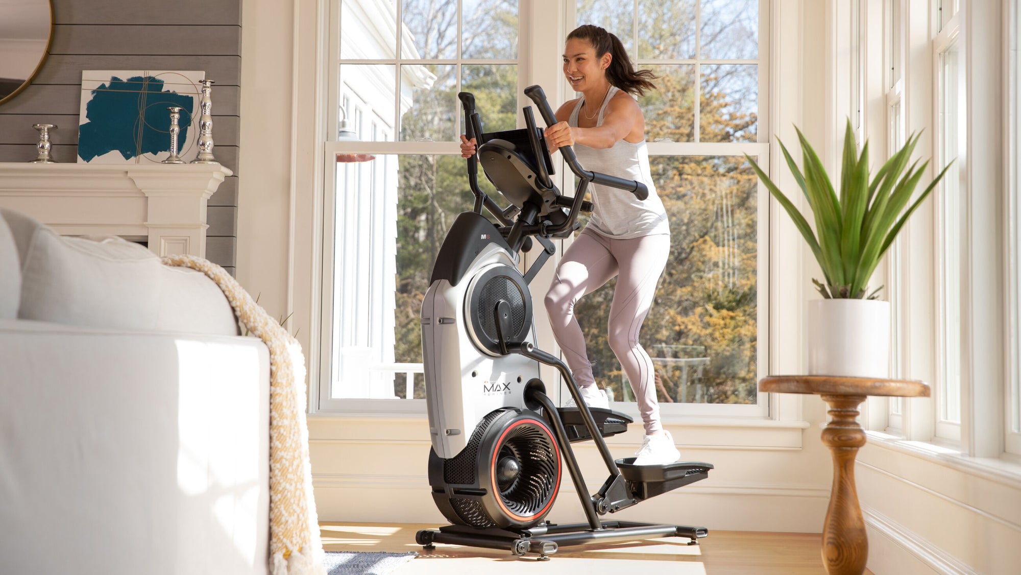 Woman exercising on a BowFlex Max Trainer M6 in a home setting.