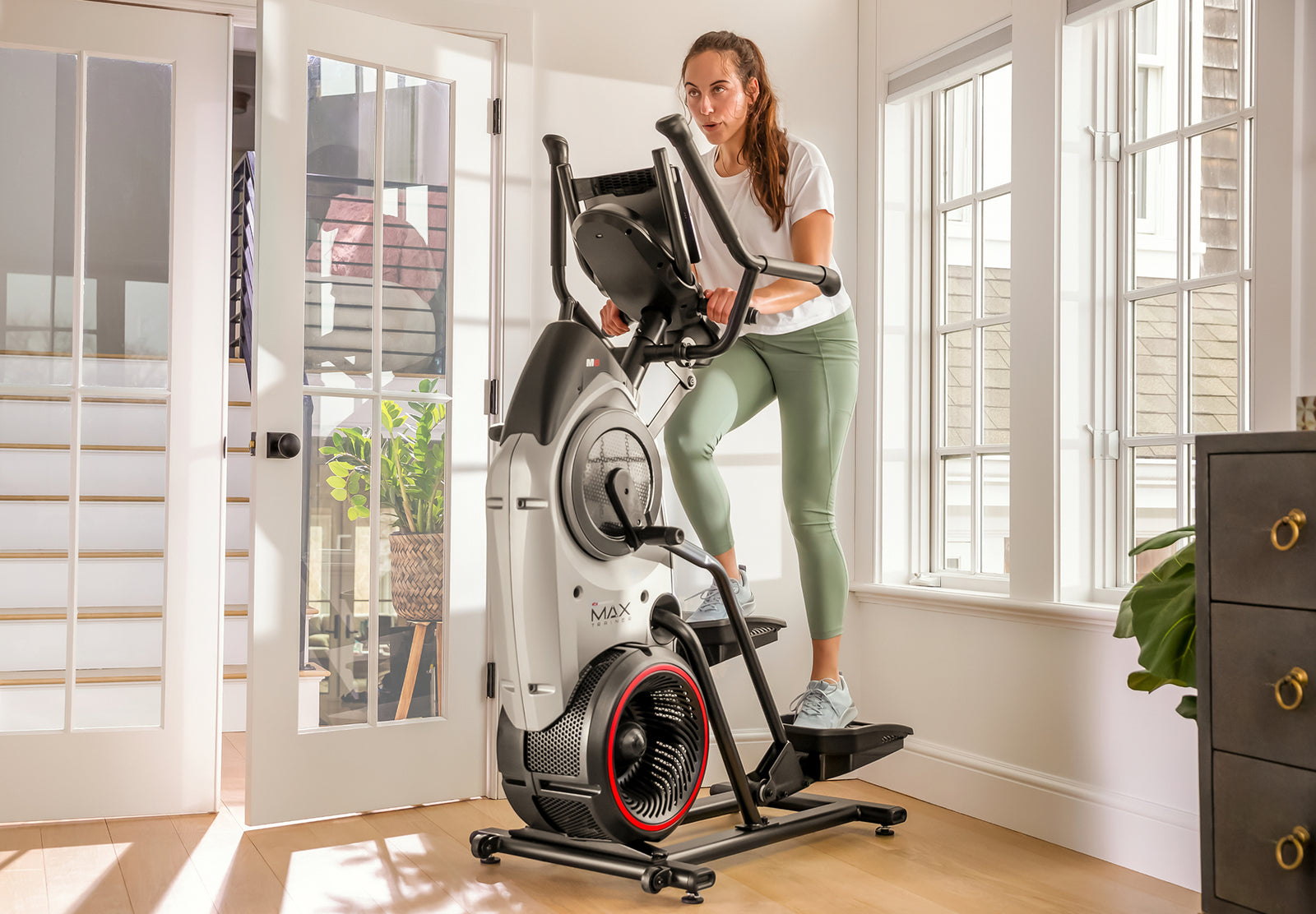 Woman exercising on a BowFlex Max Trainer M6 in a home setting.