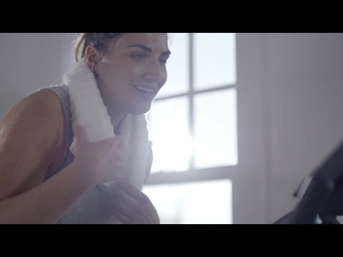 Close-up of a woman on the BowFlex C6 Bike smiling while working out with a towel around the back of her neck.