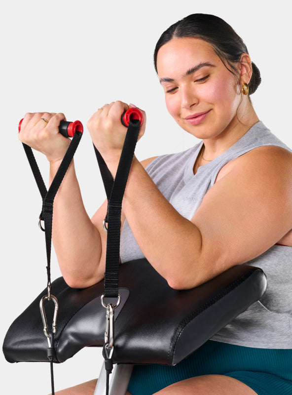 Woman using the preacher curl attachment on the BowFlex Revolution Home Gym.