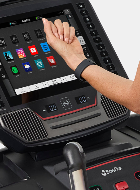 Person holding smartwatch up to the BowFlex T16 Treadmill console.