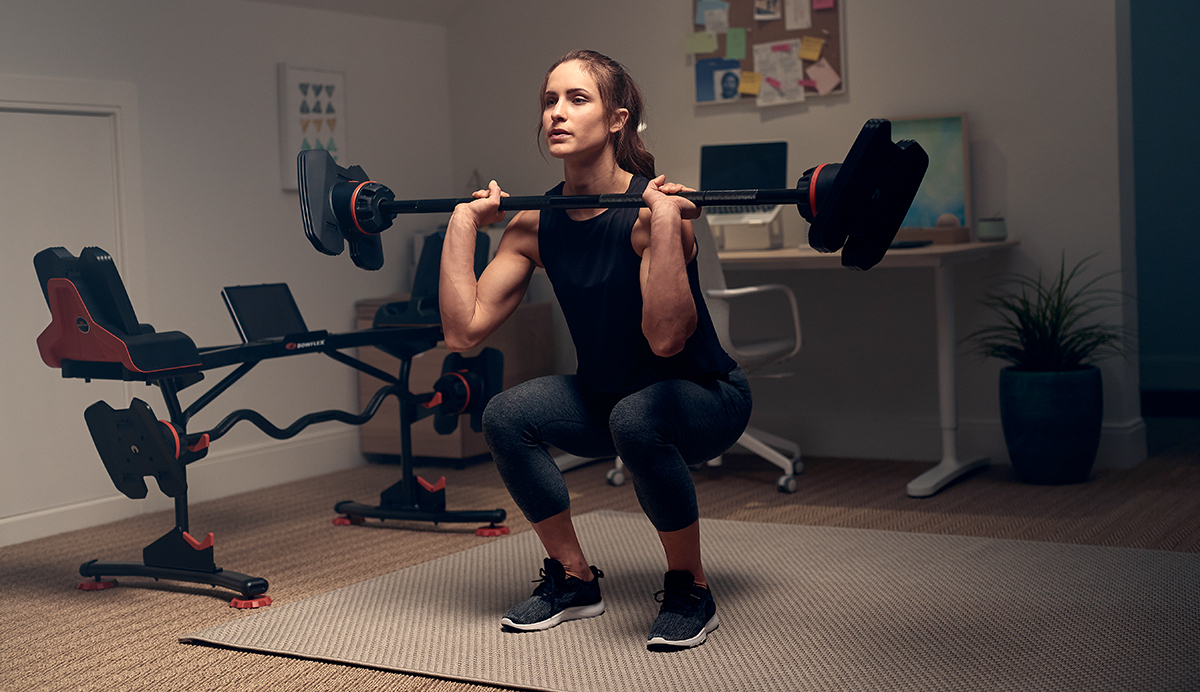 Woman doing a barbell squat exercise in a home-office