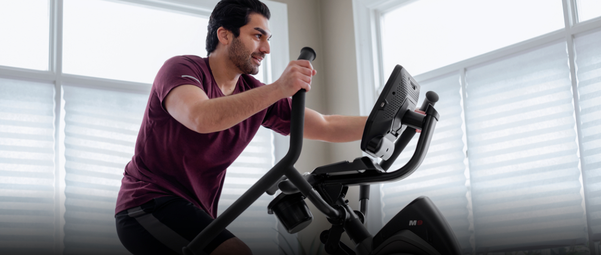 A man using a Max Trainer compact elliptical in a small apartment.